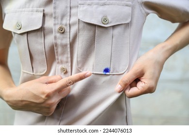Hand showing dirty blue ink stain on shirt from accident in using pen in daily life. selective focus. stain for cleaning concept. - Shutterstock ID 2244076013