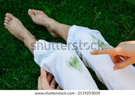 Hand showing dirty stain of grass on white pants from unexpected accident. top view. daily life stain concept. outodoors