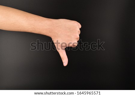 hand showing thumbs down gesture on dark background