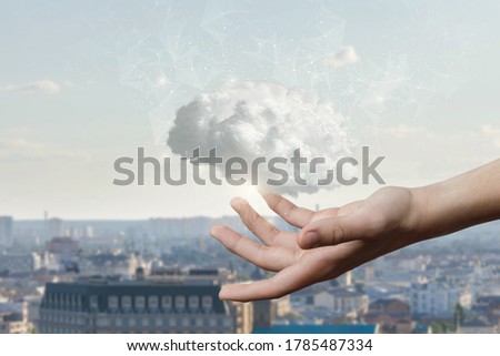 The hand shows a brain consisting of clouds on the background of the city.