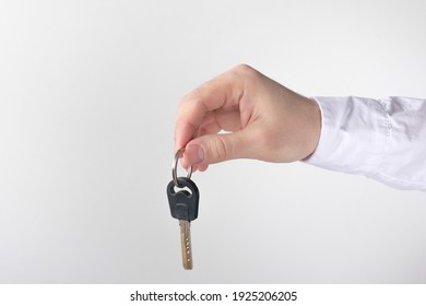 Hand Shows The Keys On A White Background, Copy Space