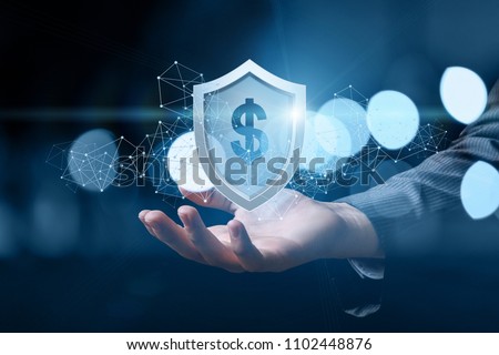 Hand shows a shield with dollar sign on dark background. Concept of protection money.