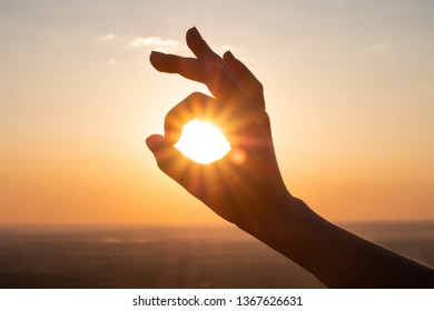 hand sign and sun rays going through hands at sunset - Powered by Shutterstock