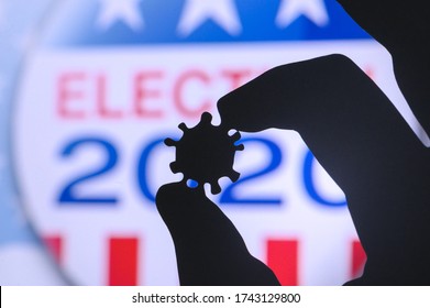 Hand Silhouette Hold Covid 19 Virus. Logo Of USA Presidental Election 2020 In Background. US Presidential Elections Are Threatened By Coronavirus And May Be Postponed