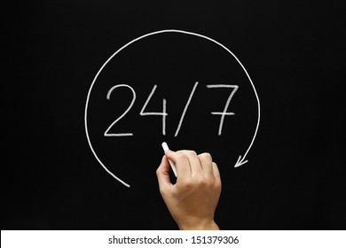 Hand sketching 24/7 concept with white chalk on a blackboard.