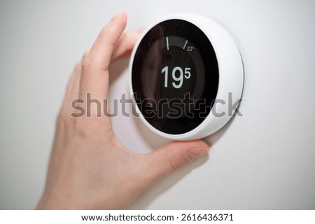 A hand skillfully adjusts a modern smart thermostat to achieve optimal home comfort and energy efficiency