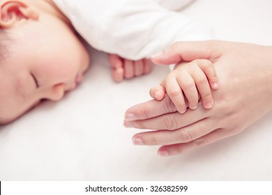 Hand of sleeping baby in the hand of mother close up on the bed, New family and baby protection from mom concept