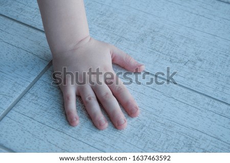 Hand of a small child on a wooden background.