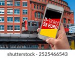 Hand with smartphone or cellphone and message d-ticket 58 euro with hamburg city background