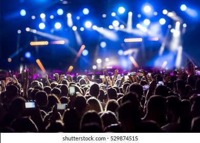Hand with a smartphone records live music festival, Taking photo of concert stage, live concert, music festival, happy youth, luxury party, landscape exterior. - Shutterstock ID 529874515