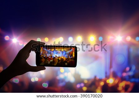 Hand with a smartphone records live music festival and taking photo of concert stage live concert luxury party in facebook live.