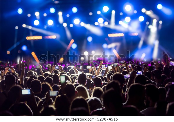 Hand with a smartphone records\
live music festival, Taking photo of concert stage, live concert,\
music festival, happy youth, luxury party, landscape\
exterior.