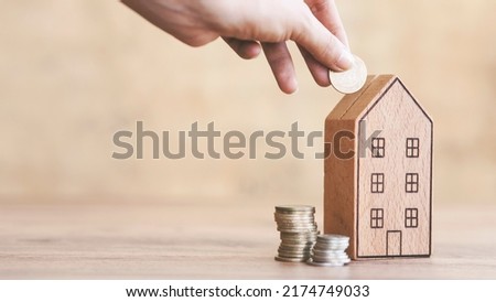hand of someone put coin to house money box with step of growing coins, money saving or investing for home lone or real estate concept