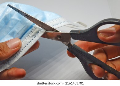 The Hand Of Someone Who Is Cutting A Used Mask That Is No Longer Suitable For Use