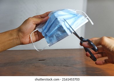 The Hand Of Someone Who Is Cutting A Used Mask That Is No Longer Suitable For Use