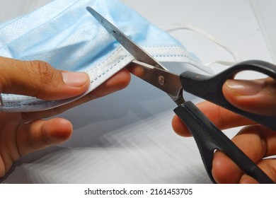 The Hand Of Someone Who Is Cutting A Used Mask That Is No Longer Suitable For Use