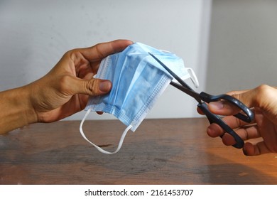 The Hand Of Someone Who Is Cutting A Used Mask That Is No Longer Suitable For Use