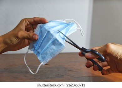 The Hand Of Someone Who Is Cutting A Used Mask That Is No Longer Suitable For Use