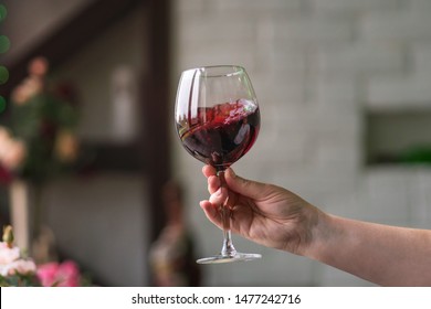 Hand sommelier holding glass of red wine. Swirling red wine glass in wine tastings. Wine tour. Space for text.
 - Powered by Shutterstock