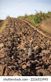 A Hand Spade Stands In A Freshly Plowed Field