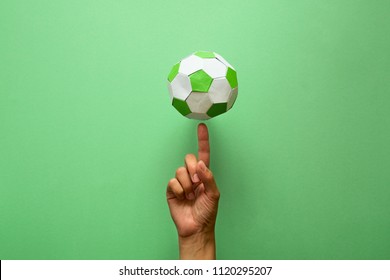 Hand Spinning Paper Soccer Ball On Green Background. Origami. Paper Craft. Soccer Game Concept.