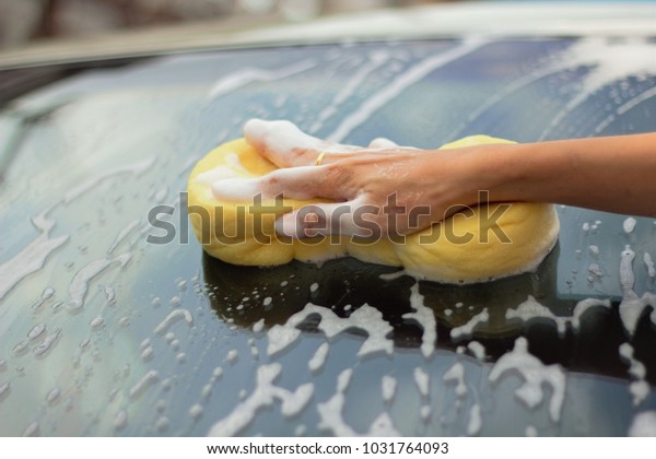 Hand with a sponge to\
clean the car.