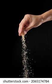 Hand Sprinkling Brown Sugar Isolated On Black Background