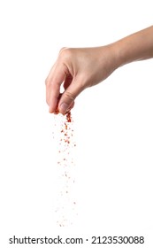 Hand sprinkling cayenne pepper isolated on white background