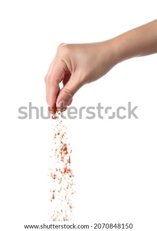 Hand sprinkling cayenne pepper isolated on white background