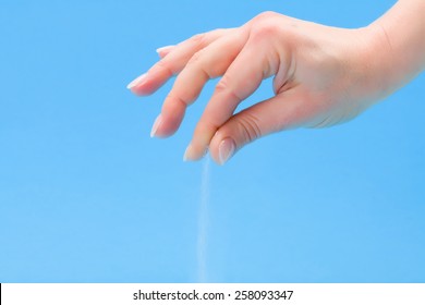 Hand Sprinkling Salt On Blue Background