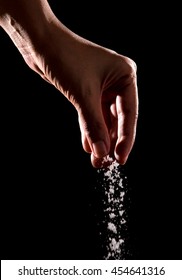 Hand Sprinkling Salt,salt Over Black Background.