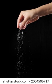 Hand Sprinkling Sugar Isolated On Black Background