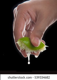 Hand squeeze lime with lime drop on black background