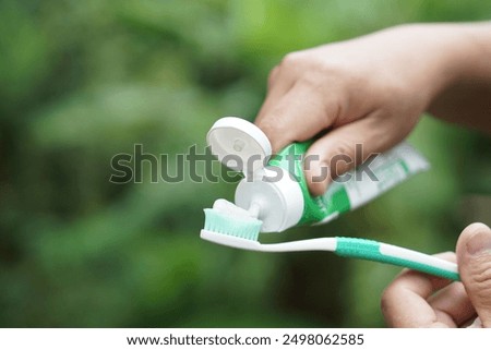 Hand squeezes toothpaste on toothbrush. Concept, dental health care. Brush teeth with fluoride toothpaste for hygiene, clean and strong teeth. Prevention from tooth decay.                             
