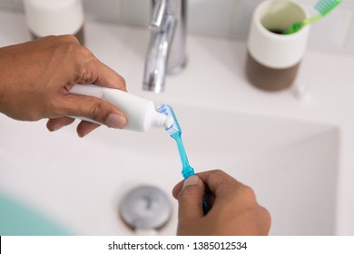 Hand Squeezing Tooth Paste To The Brush In The Morning