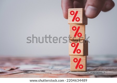 Hand stacking red percentage sign symbol on wooden cube block for financial increase interest rating and dividend from investment growth concept.