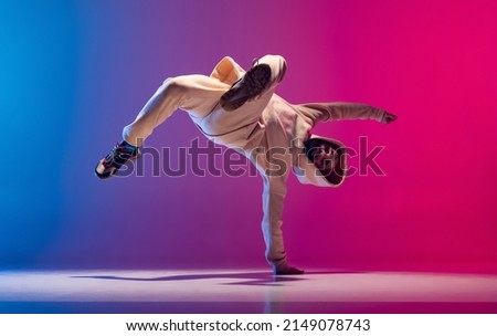 Hand stand. Studio shot of young flexible sportive man dancing breakdance in white outfit on gradient pink blue background. Concept of action, art, beauty, sport, youth. Dancer shows breakdance ストックフォト © 