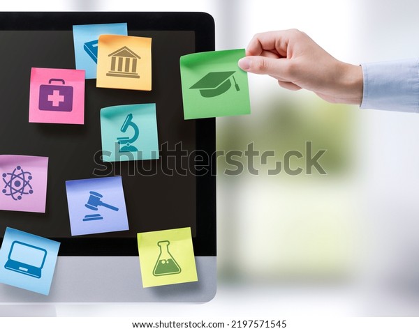 Hand sticking notes with\
educational subjects icons on a computer screen, online learning\
concept