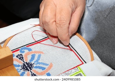 Hand stitching a needlepoint pulling thread and needle through fabric