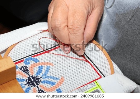 Hand stitching a needlepoint pulling thread and needle through fabric