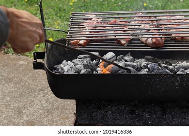 Hand Stoking The Fire With Charcoal On A Barbecue With Veal.