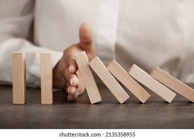 hand stops falling wooden domino blocks, risk insurance concept, crisis manager, domino principle - Shutterstock ID 2135358955