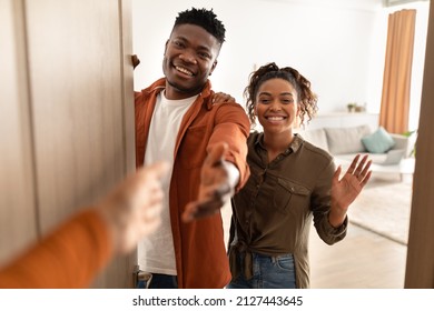 Hand Stretching For Handshake To Happy African American Couple Standing Opening Doors Of Their Home. Welcome, Nice To Meet You. Great Service And Partnership Concept. Selective Focus