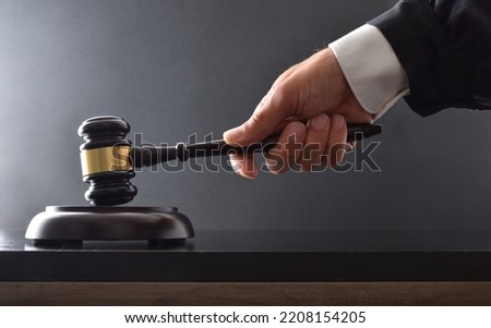 Hand striking on wooden base with judge's mallet on black table and black isolated background.  Front view.