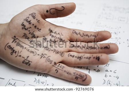 Hand of student with cheat sheet for math exam - selective focus