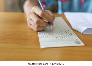 Hand Of Student Holding A Pencil Taking School Exam At The Test Center Of College Or University Campus. Educational Or Academic Picture Concept Shot In Selective Focused Mode. Test Paper For Learner.