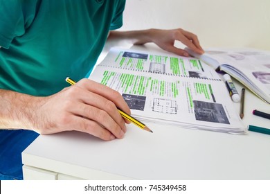 Hand Of A Student Holding A Yellow Pencil While He Reads His Books And Class Notes With Green Marker, Man Studing Art History And Architecture Focused On Achieve The Best Scores In His Exam. 