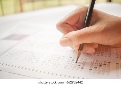 hand student testing in exercise and taking fill in exam carbon paper computer sheet with pencil at school test room, education concept - Shutterstock ID 662982442