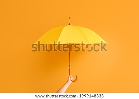 Hand with stylish umbrella on color background