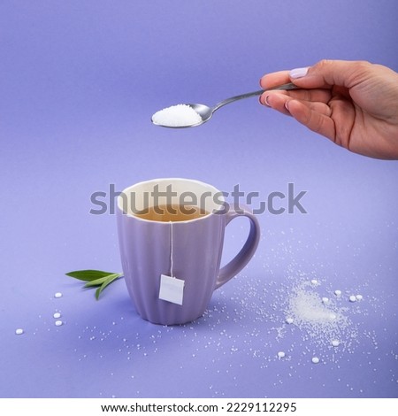 Hand with sugar. Cup of tea. Artificial sugar on a violet background, top view.
